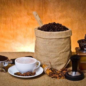 set of coffee, cup of coffee,ground coffee in portafilter,cinnamon, star anise, tamper and coffee grinder